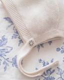 Detail of off white cashmere bonnet chin tie with crystal button closure