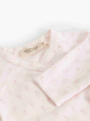 A close-up of a baby long-sleeve top by Marni, featuring a pale pink and white micro-floral pattern, a scalloped neckline, and a visible brand label.