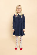 Child wearing navy knit dress with cream collar and red rose embroidery, standing full length