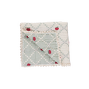 Cream and sage checked baby blanket folded into a square with one corner turned back to show the sage green reverse side, red apple embroidery, on white background