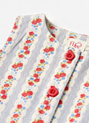 Close-up of a sleeveless top with a vertical floral stripe pattern in red, blue, and green on a white and light blue background, featuring red fabric buttons. A brand label reading 'FLO' is visible at the collar.