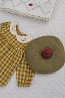 Golden green check dress collar and sleeve styled with an olive green knit beret with red pom pom and folded checkered blanket