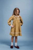 Girl standing in golden green check dress with hand on hip, front view studio portrait
