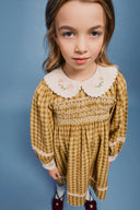 High angle portrait of girl in golden green check dress showing full length gathered skirt and lace trim