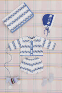 Cream cardigan and bloomer set with blue floral stripe pattern, flat lay with matching blanket, bonnet, wooden pull toy, and socks on plaid fabric