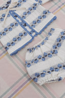Close up of cream cardigan collar with blue floral stripe pattern and scalloped trim, styled with matching bloomers on plaid fabric