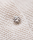 Extreme close up of a single crystal jeweled button on off white cashmere knit