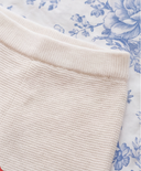 Close up of ribbed waistband on off white cashmere footed trousers, blue floral bedding