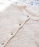 Detail of off white cashmere cardigan collar with crystal jeweled buttons along the placket