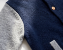 Extreme close up of navy and grey cashmere fabric seam with wooden button and pocket edge