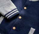 Close up of natural wooden buttons on navy cashmere letterman jacket with striped cuff trim