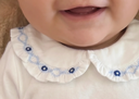 Close up of baby chin and ruffled collar with blue floral smocking embroidery