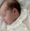Close up of sleeping newborn's face and embroidered floral collar on pearl cashmere cotton cardigan