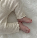 Close up of newborn feet in pearl cashmere cotton pants with scalloped cuffs