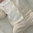 Close up of pearl cashmere cotton cardigan buttons and scalloped hem detail, pants visible