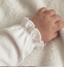 Close up of baby wearing white bodysuit with pink floral embroidered scalloped collar