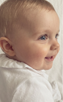 Close up of baby's face in profile, wearing white ruffled collar sleepsuit
