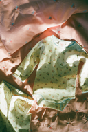 Cream baby top and leggings with soft pink poppy print, flat lay on floral fabric