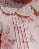 Close up of crochet Peter Pan collar and pin tucked bodice on pink floral baby dress
