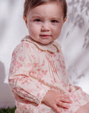 Baby girl wearing pink floral print dress with crochet collar, three quarter view
