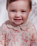 Close up of baby girl smiling in pink floral dress with crochet collar
