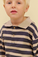 A close-up of a young child wearing a long-sleeve polo shirt with horizontal navy and beige stripes, featuring a solid beige collar and two wooden buttons.
