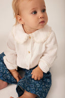 Baby wearing a white textured blouse with lace 