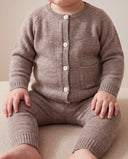 Baby sitting wearing natural melange merino wool cardigan and matching pants, close crop from chin to knees