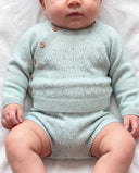 baby boy laying down in an aqua knit cardigan and matching bloomer