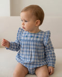 Baby girl wearing blue and white plaid ruffle sleeve romper with embroidered flowers, sitting