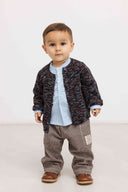 Toddler boy wearing dark brown and white pinstripe pants with black knit cardigan, blue striped shirt, and brown loafers
