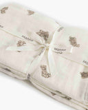 Cream muslin swaddle blanket with tan teddy bear print, folded and tied with ribbon