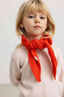 Toddler girl wearing red orange ribbed knit scarf tied around neck over pale pink cardigan