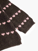 Close up of sleeve cuff on dark brown knit sweater with pink heart stripe pattern