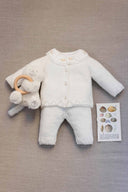 Pearl cashmere cotton cardigan and pants set flat lay with embroidered floral collar, styled with a plush teddy bear rattle and seashell illustration card