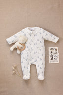 Cream teddy bear print sleepsuit with collar and front pocket, flat lay with teddy bear rattle and bird illustration card