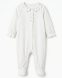 Flat lay of white footed sleepsuit with scalloped collar and pink floral embroidery on white background