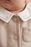 Close up of baby wearing beige melange cardigan with embroidered white collar and button placket