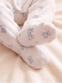 Close up of baby feet in cream teddy bear print footed sleepsuit