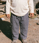 Child standing outdoors wearing grey pinstripe trousers with cargo pockets, paired with cream long sleeve top