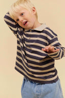Toddler boy wearing grey and oatmeal striped long sleeve polo shirt, playful pose